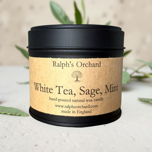 Candle in a tin labeled 'White Tea, Sage, Mint' by Ralph's Orchard on a neutral background.