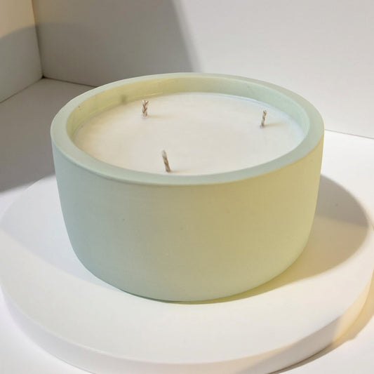 Round candle in a light green container on a white surface
