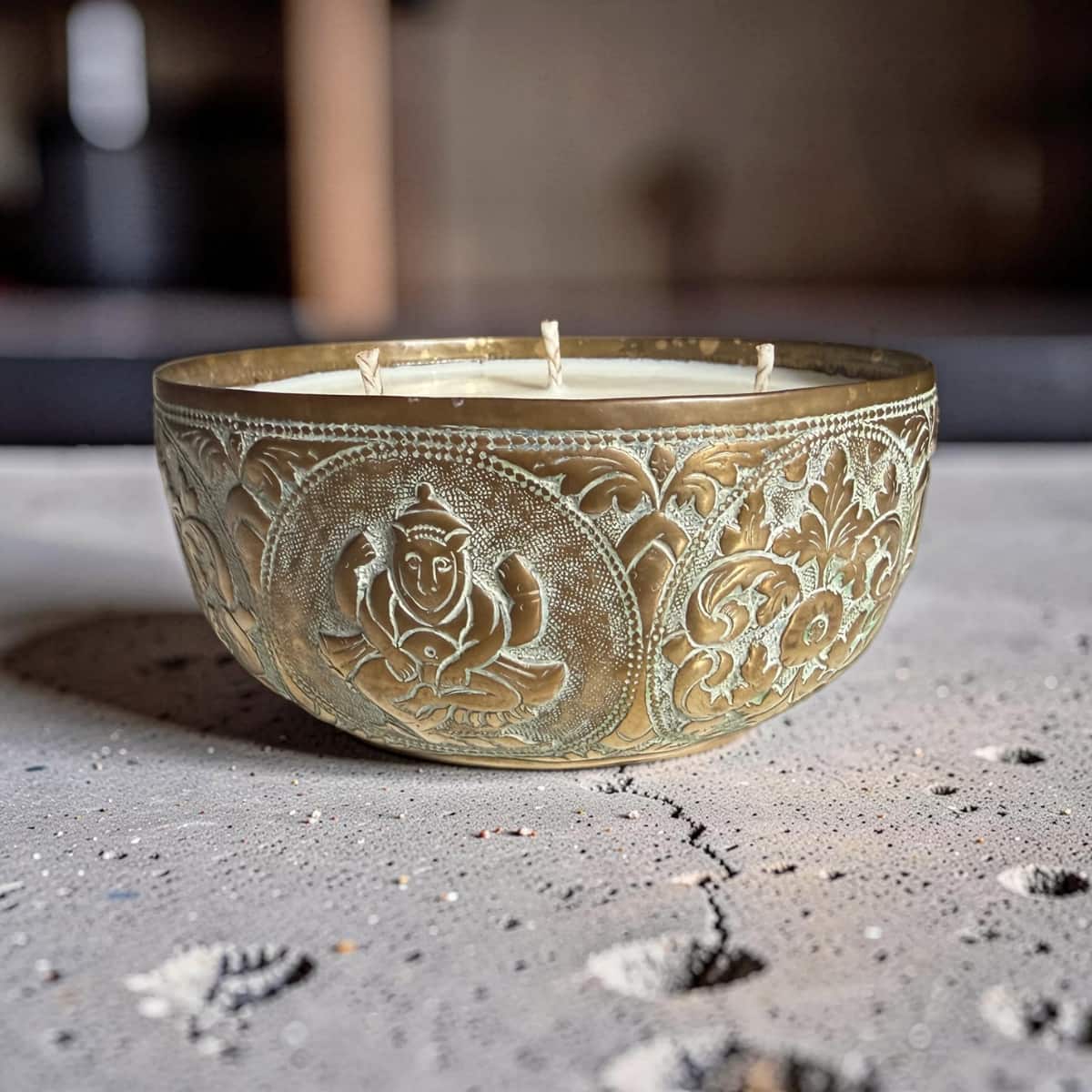 Decorative candle in an embossed metal holder on a textured surface