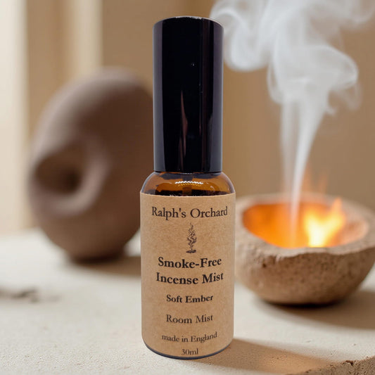 Bottle of Ralph's Orchard Smoke-Free Incense Mist with a burning candle in the background