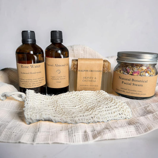 Set of natural skincare products including bottles, a jar, and a soap bar on a textured surface.