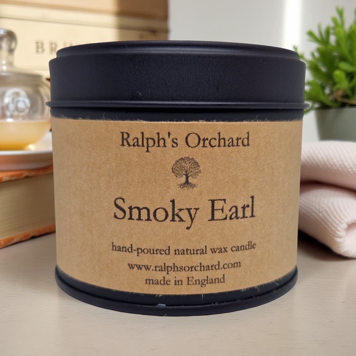 Candle labeled 'Smoky Earl' by Ralph's Orchard on a surface with a blurred background