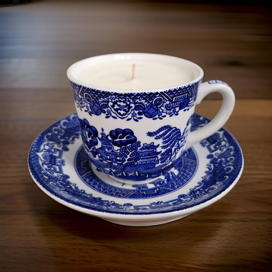 Blue and white ceramic teacup and saucer with a candle inside on a wooden surface