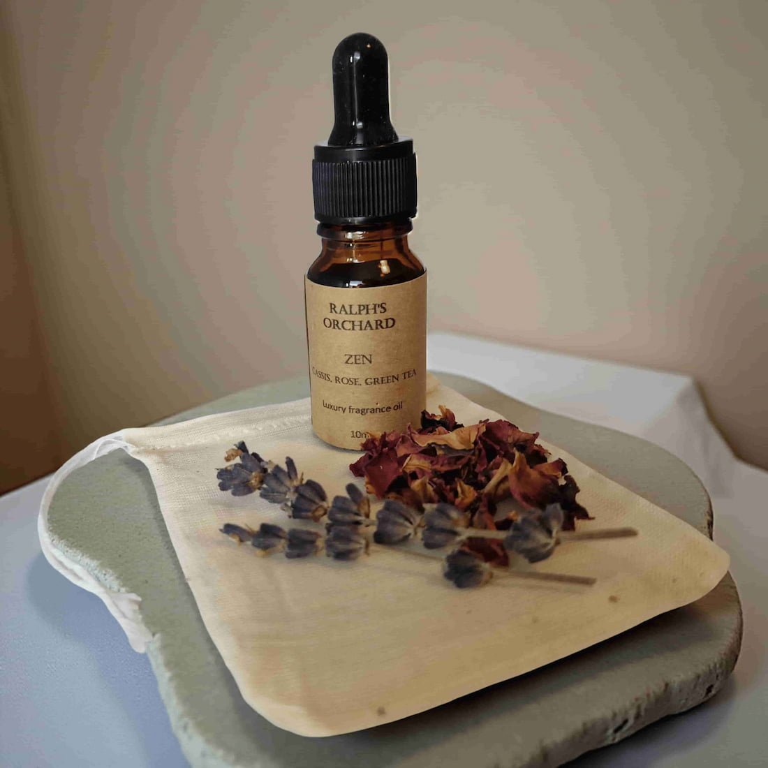 Bottle of Ralph's Orchard Zen fragrance oil on a wooden board with dried flowers.