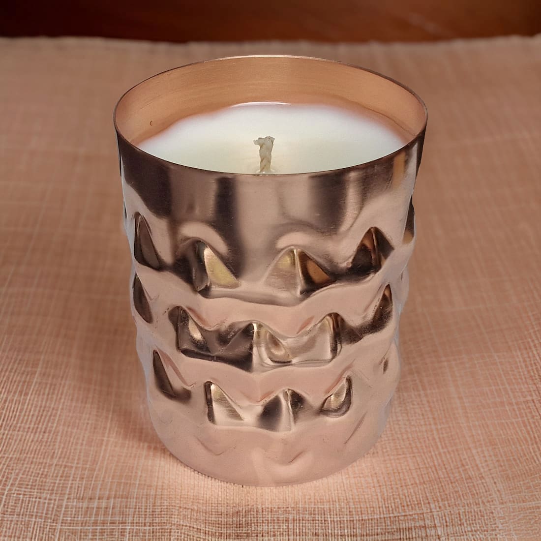 Candle in a decorative metallic holder on a textured surface