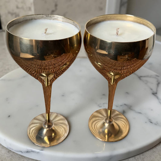 Two gold candle holders with candles on a marble surface