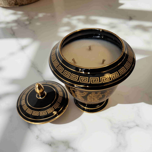 Decorative black and gold candle with lid on a marble surface