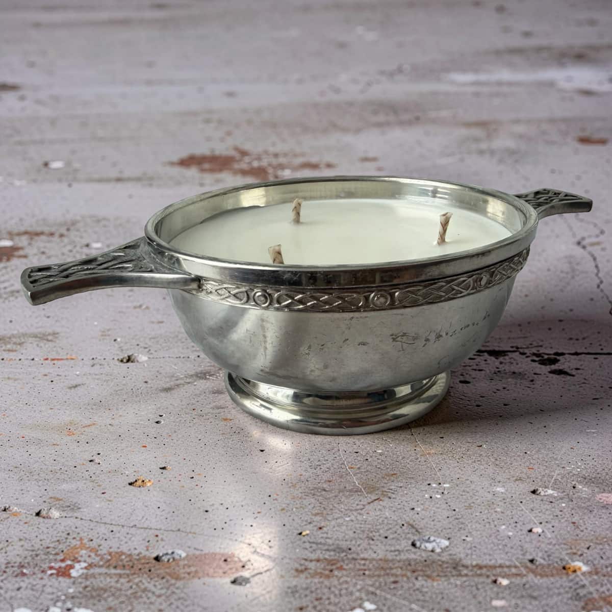 Silver candle holder with a candle on a rustic wooden surface