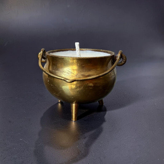 Brass cauldron with a candle on a dark background
