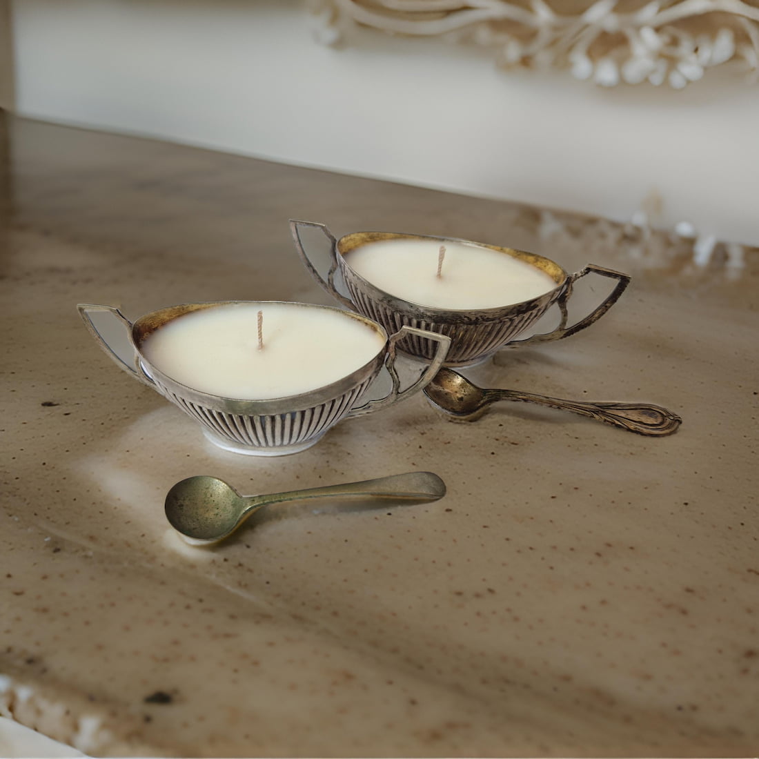 Two vintage-style teacups with candles on a textured surface
