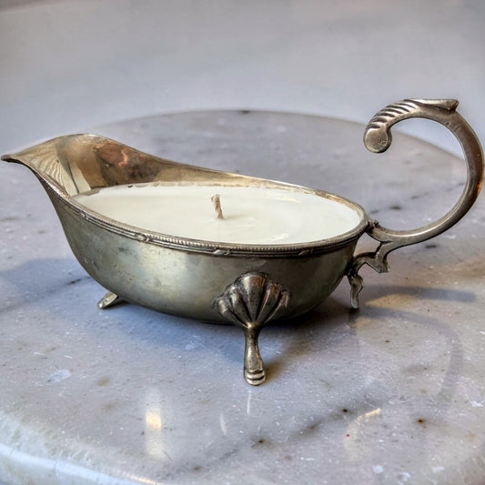 Silver gravy boat with a candle inside on a marble surface