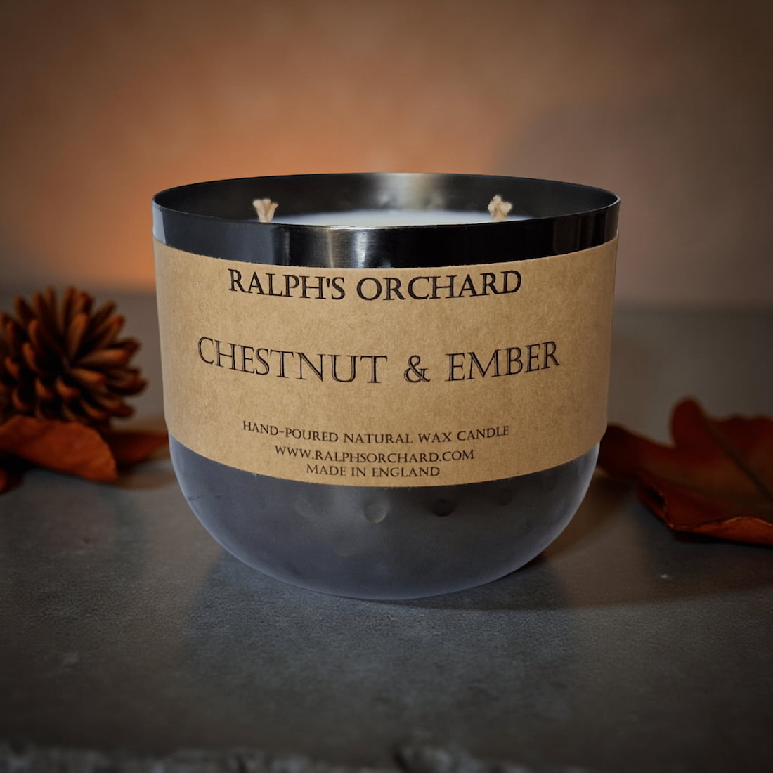 Candle with 'Ralph's Orchard Chestnut & Ember' label on a textured surface.