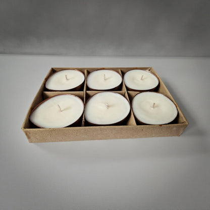 Set of six white candles in a cardboard box on a gray background