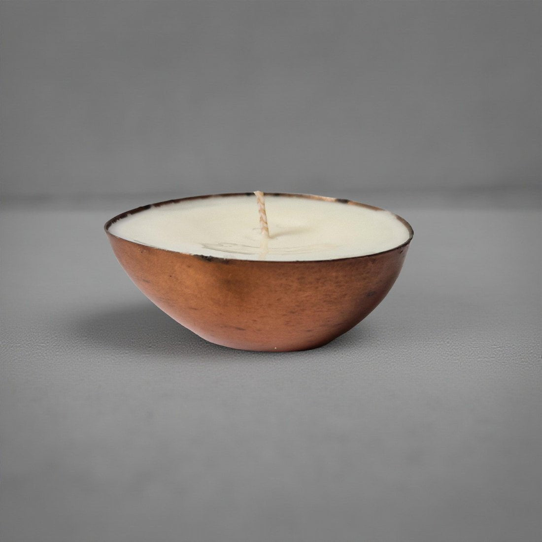 Ceramic bowl with a candle inside on a gray background