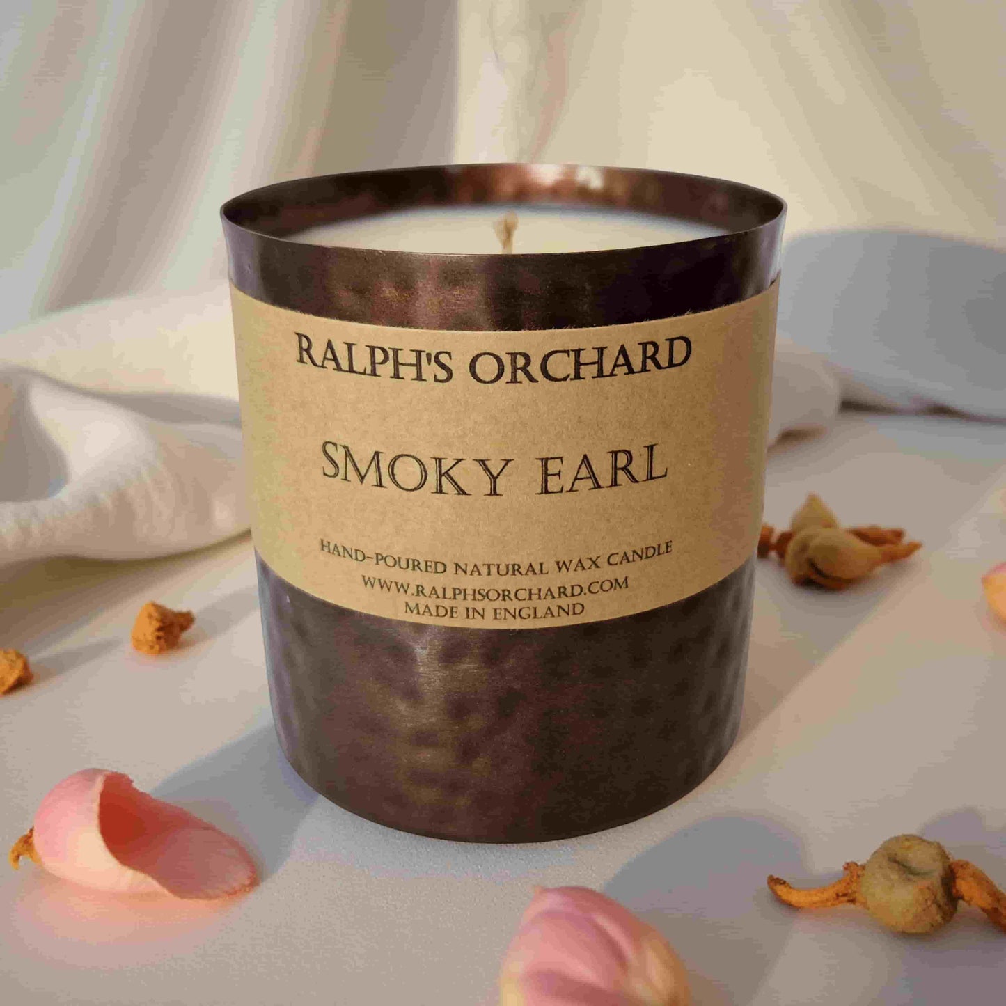 Candle labeled 'Smoky Earl' from Ralph's Orchard on a neutral background with decorative elements.