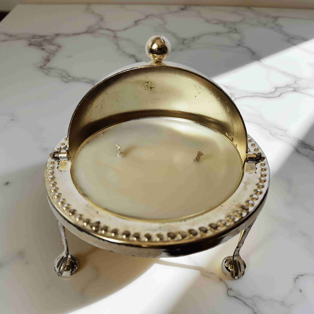 Decorative candle in a gold holder on a marble surface