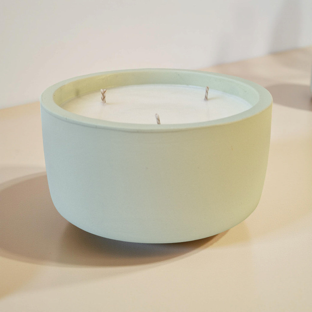 Light blue ceramic bowl with a candle on a beige surface