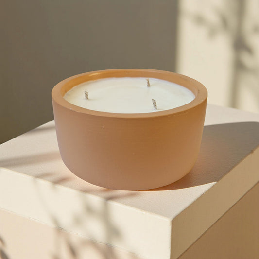 Ceramic candle holder with a white candle on a light surface with a neutral background