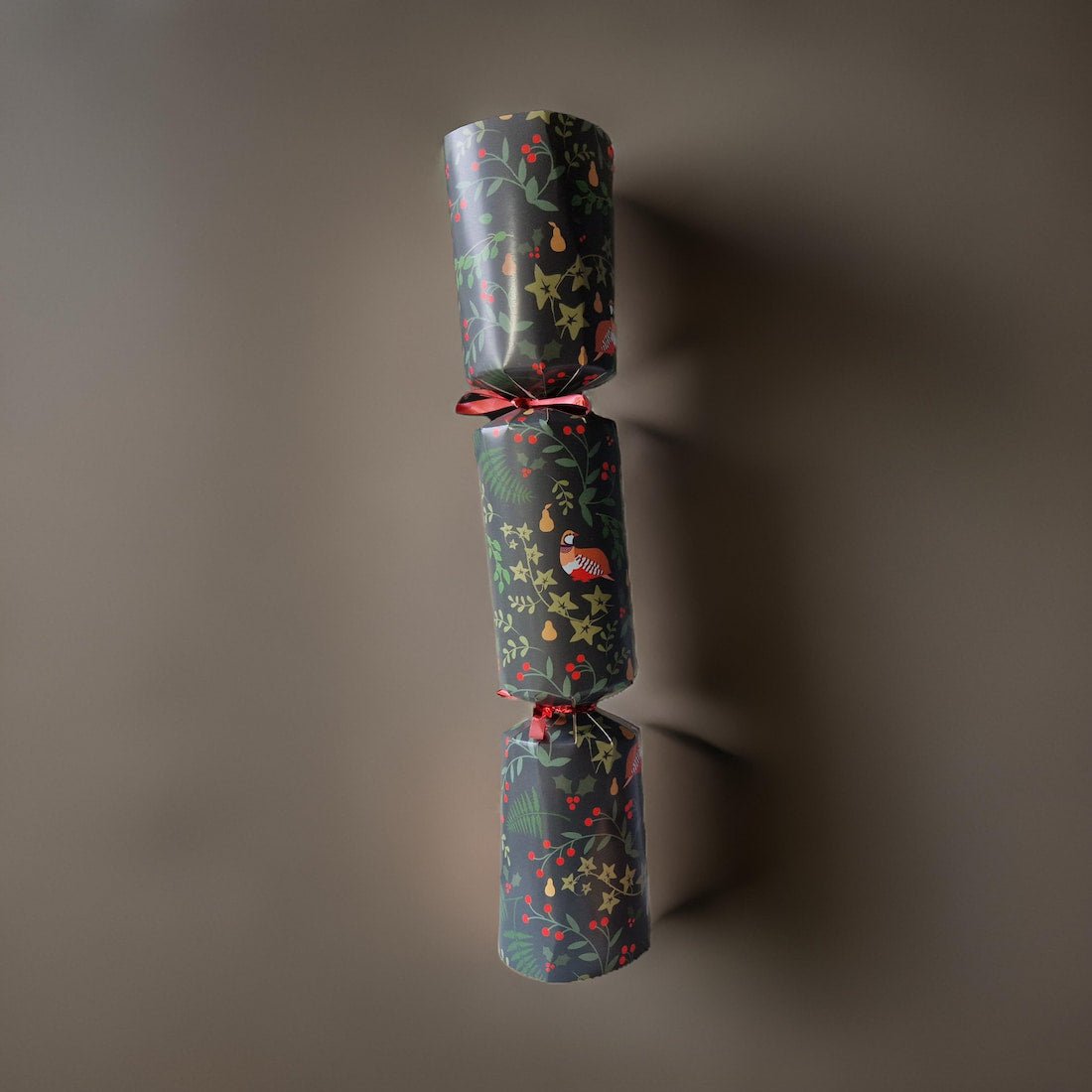 Two wrapped Christmas crackers with festive patterns on a dark background
