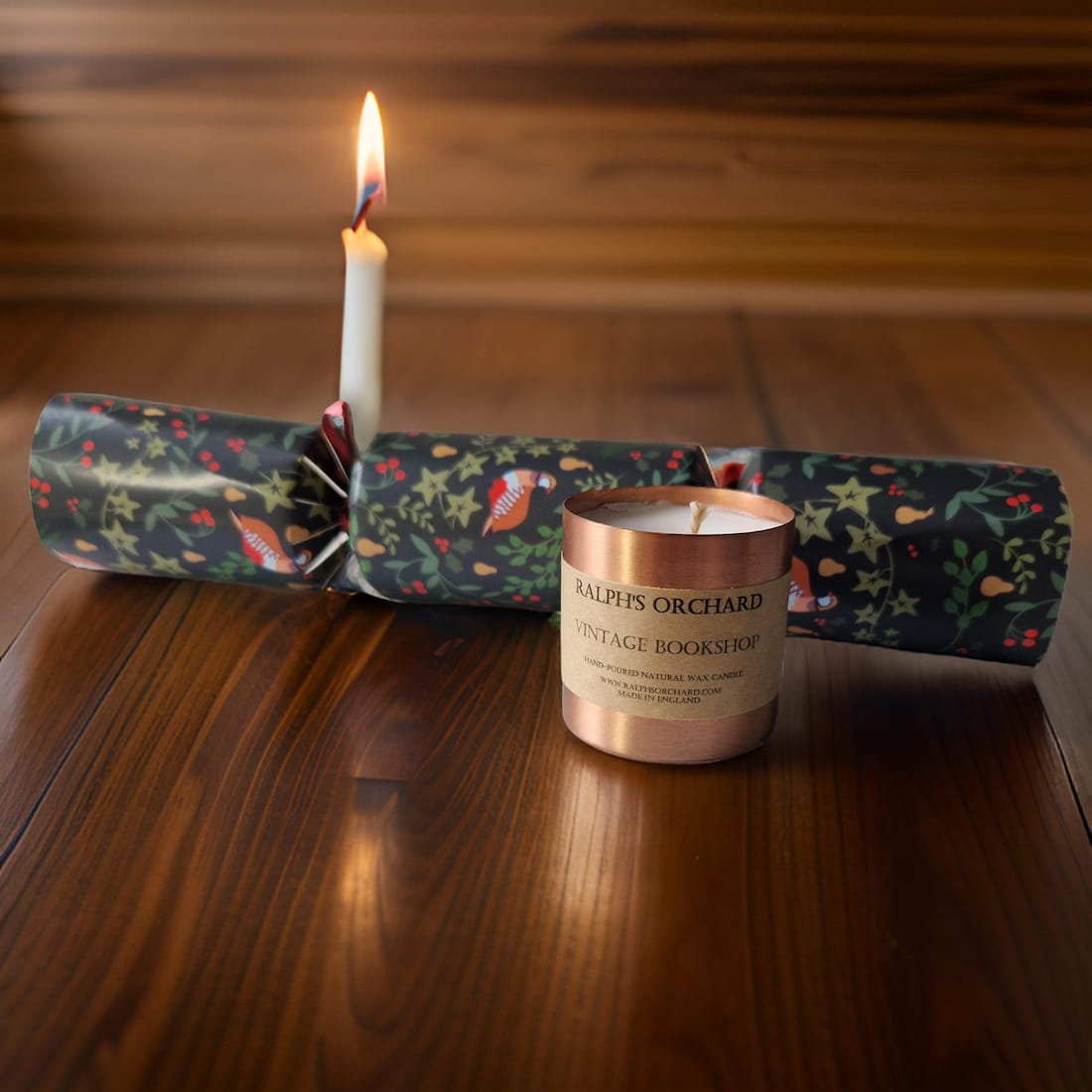 Candle in a decorative cracker with a candle labeled 'Ralph's Orchard Vintage Bookshop' on a wooden surface.
