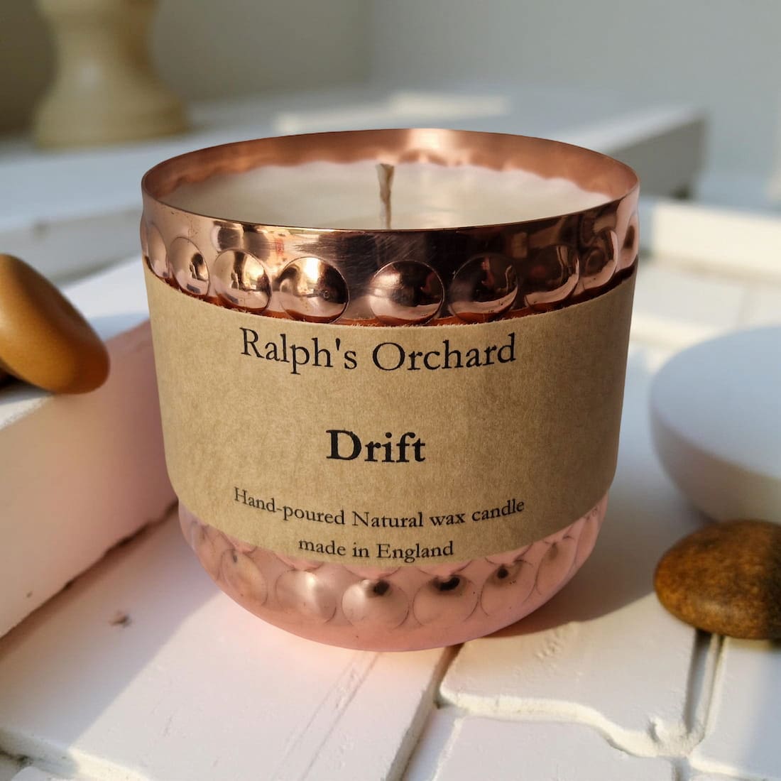 Candle with a copper lid and 'Ralph's Orchard Drift' label on a light surface.