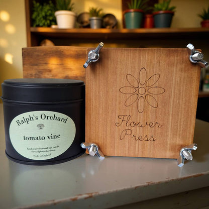 Wooden flower press with 'Ralph's Orchard' candle on a surface