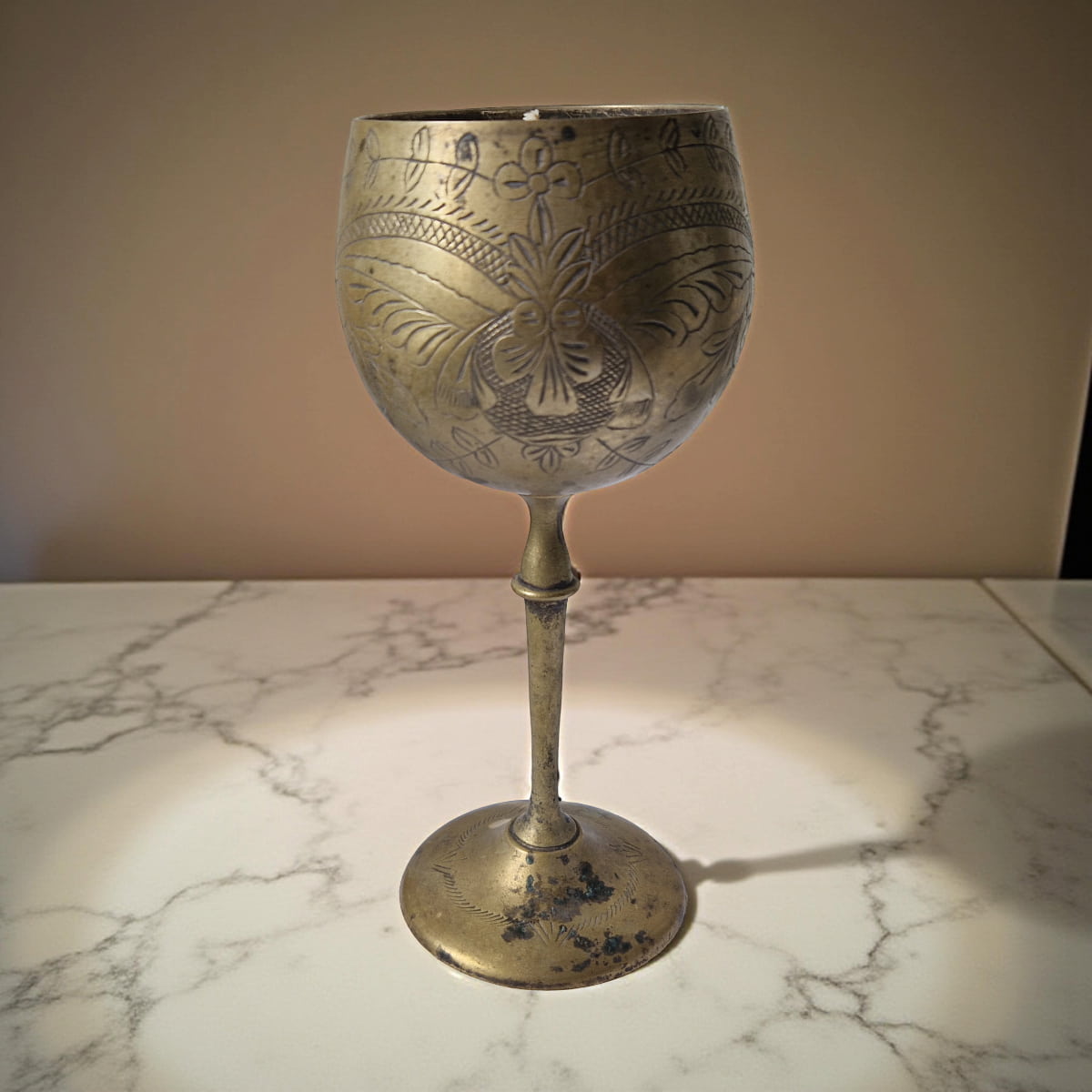 Decorative brass goblet on a marble surface with a neutral background