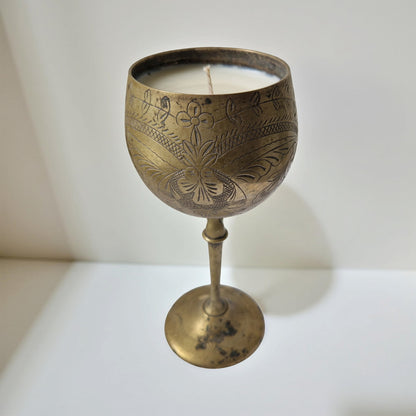 Decorative brass candle holder with a lit candle on a white background