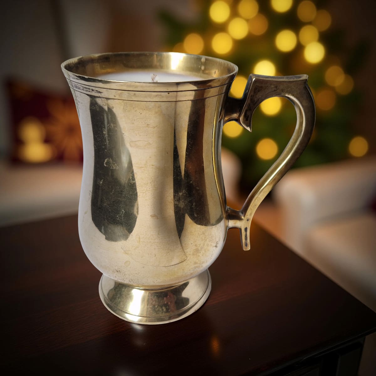 Silver mug on a wooden surface with a blurred festive background