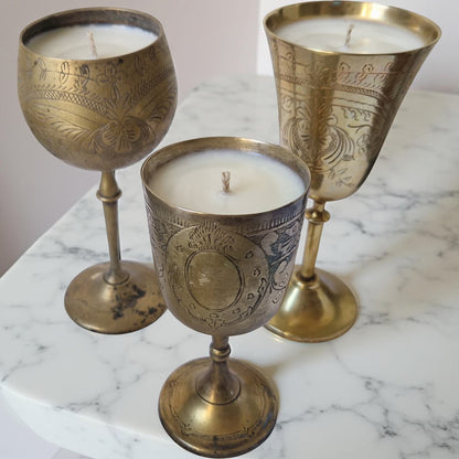 Three ornate brass candle holders with candles on a marble surface