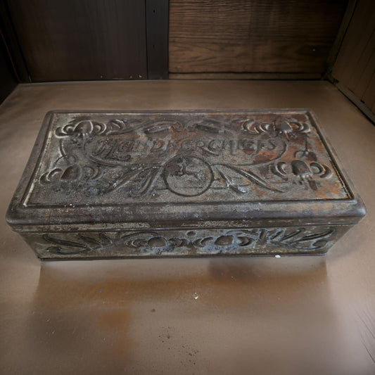 Rustic metal box with engraved design on a wooden surface