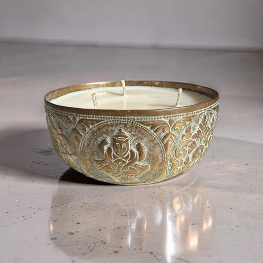 Decorative candle in an ornate metal holder on a light surface.