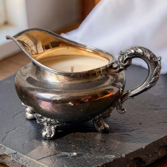 Silver gravy boat with candle inside on a dark surface