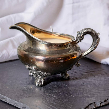Silver gravy boat with candle inside on a dark surface