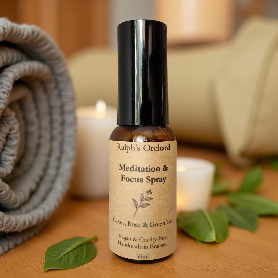 Bottle of Ralph's Orchard Meditation & Focus Spray on a wooden surface with candles and leaves.