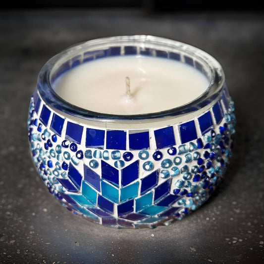 Candle in a blue mosaic holder on a dark surface
