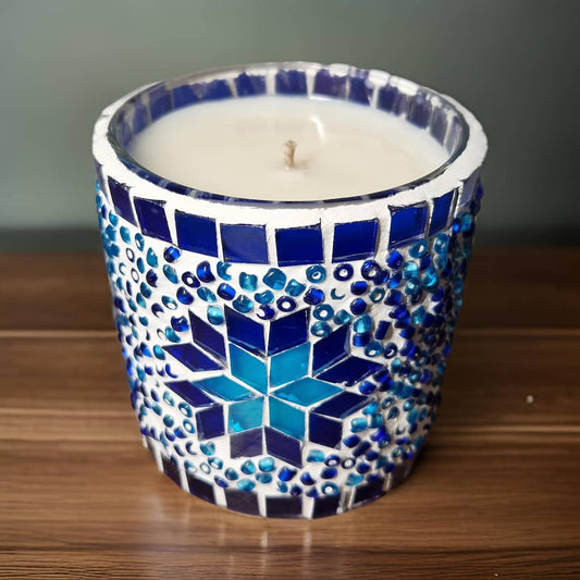 Candle in a blue and white mosaic container on a wooden surface