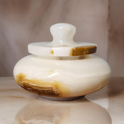 Marble-like container with a lid on a reflective surface