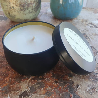 Candle in a black container with a label on a textured surface