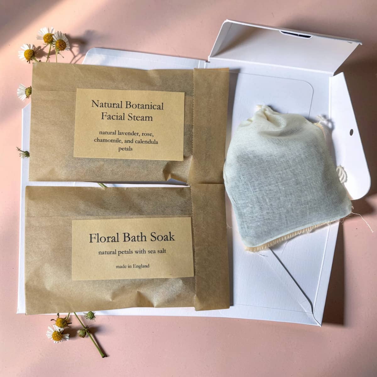 Two natural skincare products in brown paper packaging with labels on a pink background.