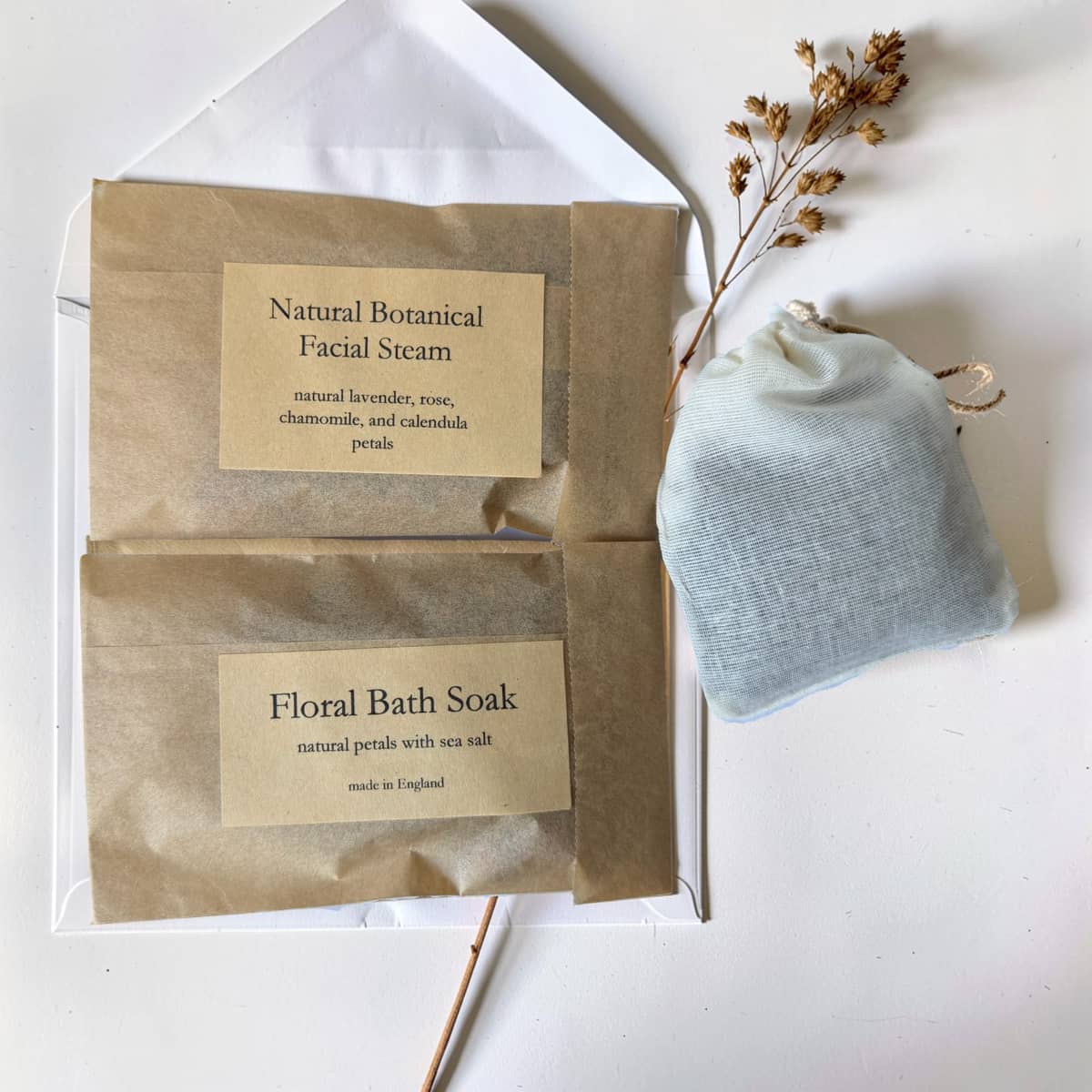 Two brown paper packages labeled 'Natural Botanical Facial Steam' and 'Floral Bath Soap' on a white background with a gray soap bar.