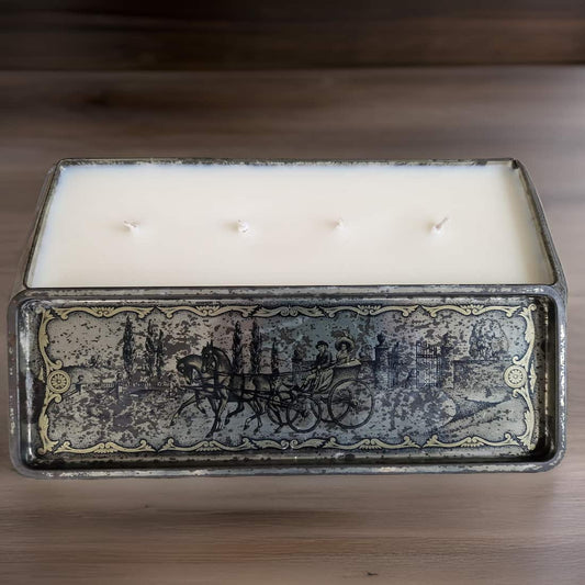 Rectangular candle in a decorative metal container with engravings on a wooden surface