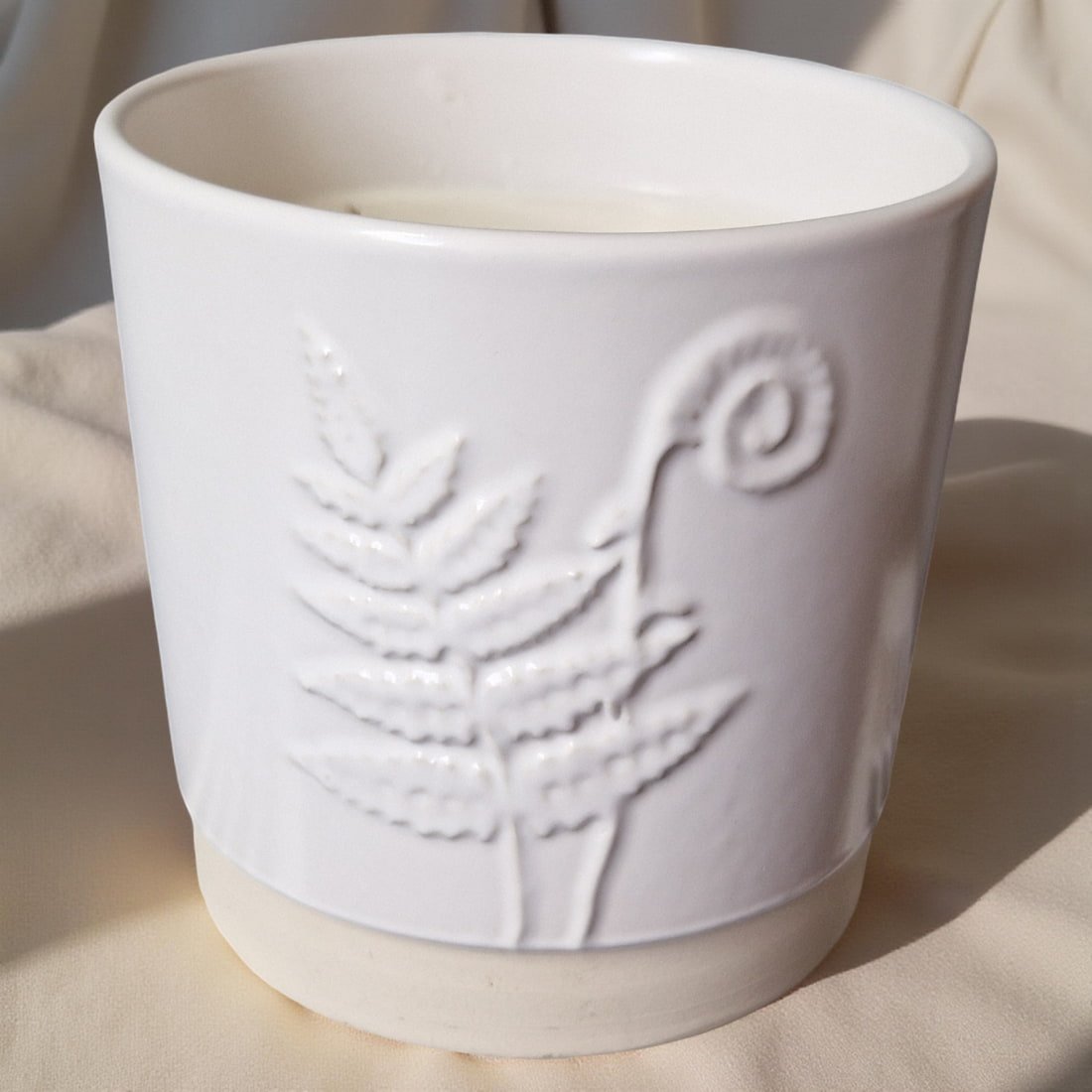 White ceramic pot with embossed design on a light background