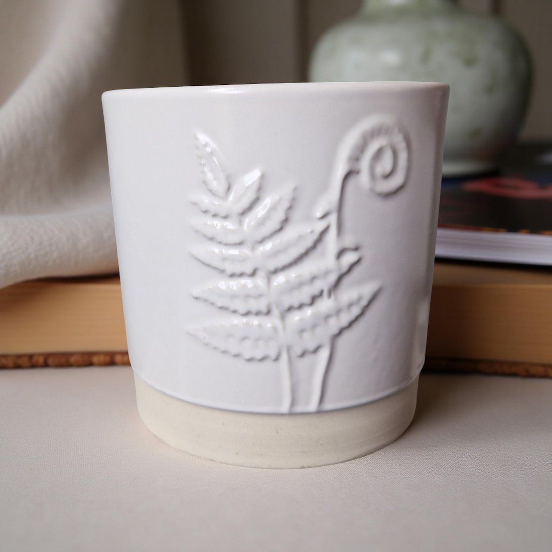 White ceramic pot with embossed design on a surface