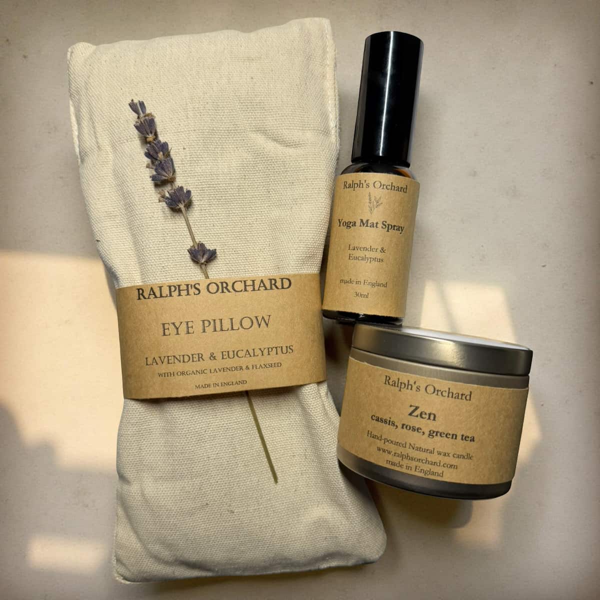 Eye pillow with lavender and eucalyptus, yoga mat spray, and candle labeled 'Ralph's Orchard' on a neutral background.