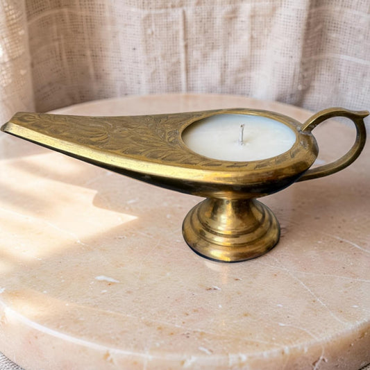 Brass oil lamp with a candle on a marble surface