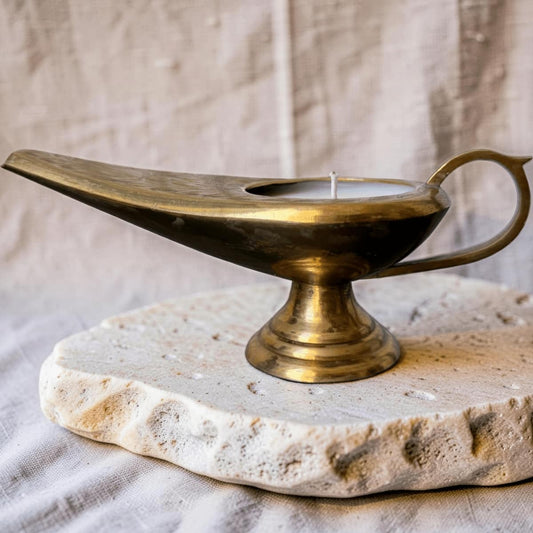 Brass oil lamp on a stone base with a neutral background