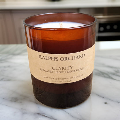 Candle labeled 'Ralph's Orchard Clarity' on a marble surface