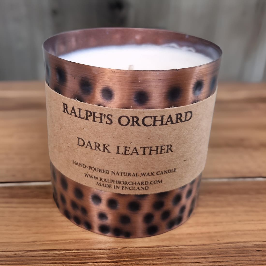 Candle with 'Ralph's Orchard Dark Leather' label on a wooden surface