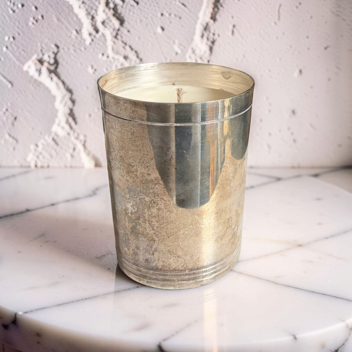 Silver candle holder with a candle on a marble surface